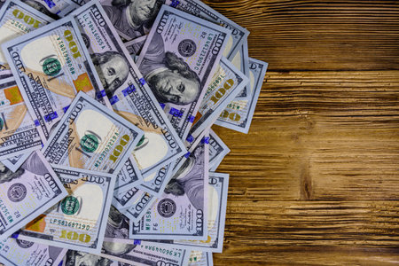 Heap of one hundred dollar banknotes on wooden background. Top view