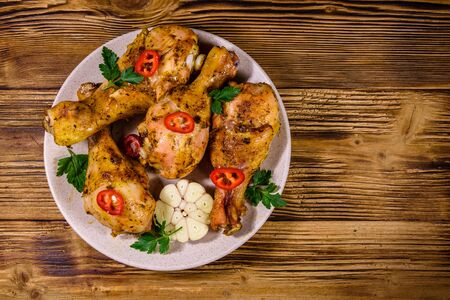 Baked chicken legs with parsley, garlic and sliced red hot pepper in plate. Top viewの写真素材