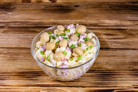 Salad with marinated mushrooms, sausage, onion, boiled potato and mayonnaise on wooden tableの写真素材