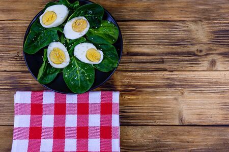 Spinach leaves and halved boiled eggs on black plate. Top viewの写真素材