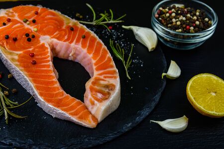 Raw salmon steak and spices on slate boardの写真素材