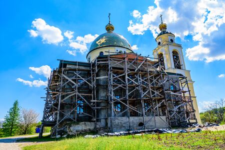 Reconstruction of old orthodox church in ukrainian countryside. Wooden scaffoldingの写真素材