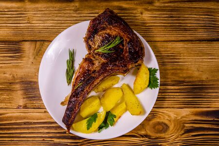 Plate with roasted ribeye steak on rustic wooden table. Top viewの写真素材