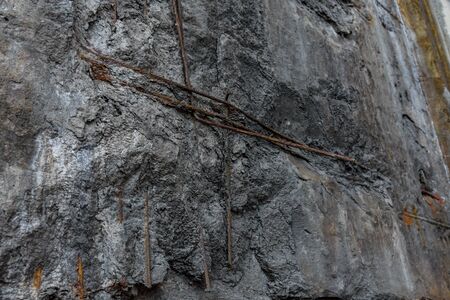 Old damaged concrete wall with rusty armature rodsの写真素材