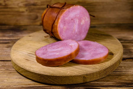Cutting board with sliced sausage on rustic wooden tableの写真素材
