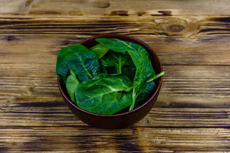 Ceramic bowl with spinach leaves on wooden tableの写真素材