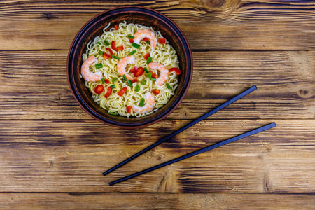 Instant noodle with shrimps, red pepper and green onion in ceramic bowl. Japanese food. Top view