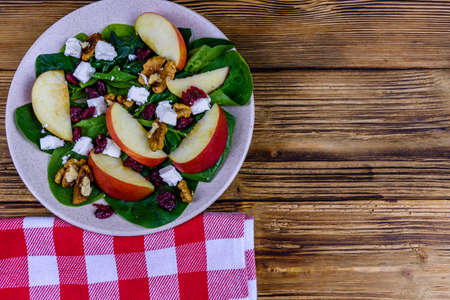 Salad with spinach leaves, feta cheese, cranberries, walnuts and apple in ceramic plate. Top viewの写真素材