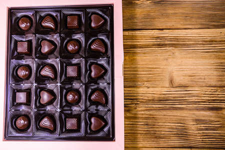 Heap of chocolate candies in brown box on wooden table. Top viewの写真素材