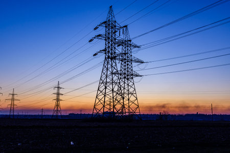 High voltage power line in field at sunset