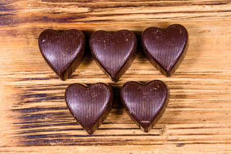 Heap of heart shaped chocolate candies on wooden table. Top view. Valentine day conceptの写真素材