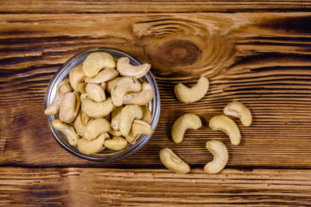 Glass bowl with raw cashew nuts on wooden table. Top viewの写真素材