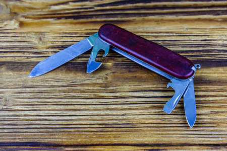 Unfolded all purpose red pocket knife on a wooden backgroundの写真素材