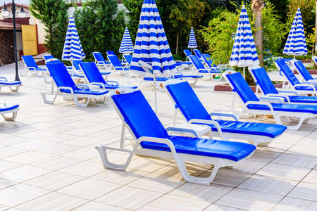 Empty chaise lounges and sun umbrellas near swimming poolの写真素材