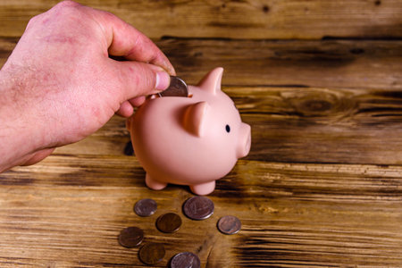 Man putting cent coin in pink piggy bank