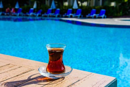 Black tea in traditional turkish glass on table near swimming poolの写真素材