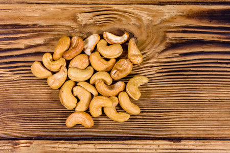 Pile of roasted cashew nuts on wooden table. Top viewの写真素材