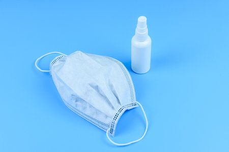 Protective face mask and hand sanitizer on blueの写真素材