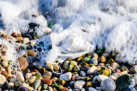 A disposable face mask discarded on pebble at beachの写真素材