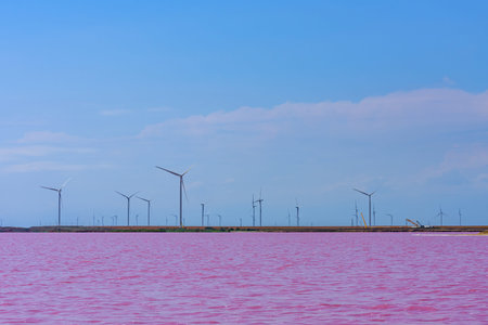 Wind turbines at shore of lake with pink water. Clean energy. Ecological concept