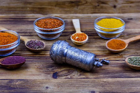 Spoons and bowls with oriental spices and spice mill on wooden tableの写真素材