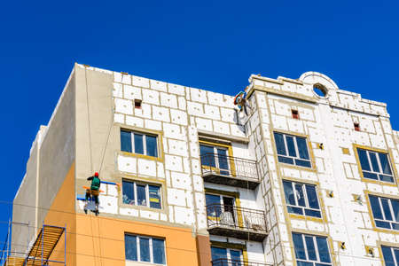 Insulation of multistory residential building with styrofoam. Rope access workingのeditorial素材