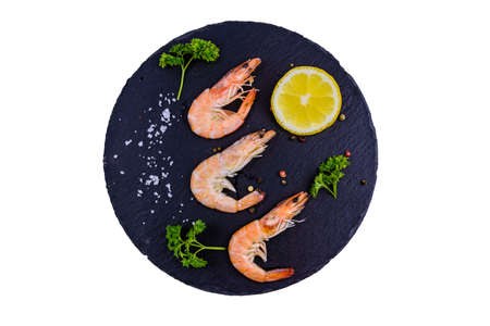 Shrimps with spices, salt, lemon and parsley on slate board isolated on white backgroundの写真素材