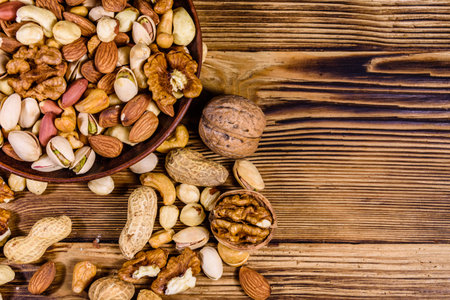 Various nuts (almond, cashew, hazelnut, pistachio, walnut) in ceramic plate on wooden table....