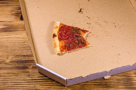 Last piece of pizza with salami sausage and parmesan cheese in cardboard box