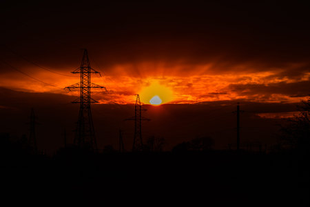 High voltage power line at sunset. Silhouettes of metal pillars