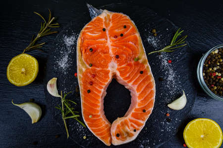 Raw salmon steak and spices on slate board. Top viewの写真素材