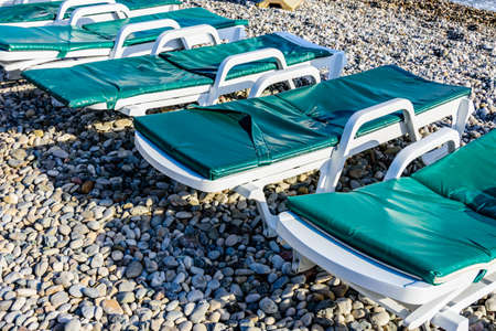 Empty chaise lounges on pebble at beachの写真素材