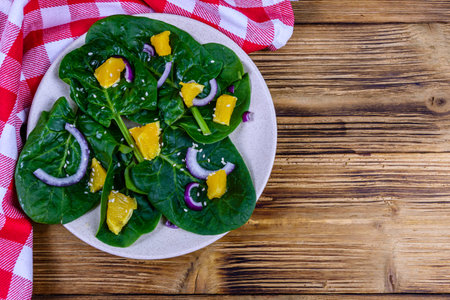 Salad with spinach leaves, pieces of orange, sesame seeds and onion in ceramic plateの写真素材