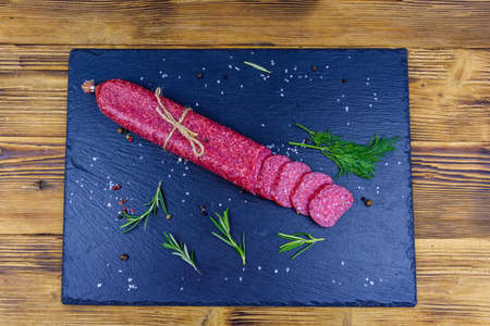 Sliced dry smoked salami sausage on slate board. Top viewの写真素材