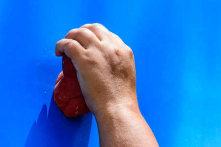 Young woman hand holding hook at blue climbing wallの写真素材