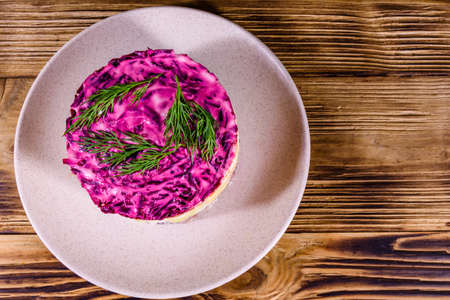 Ceramic plate with russian traditional new year salad herring under fur coat (shuba) and on rustic wooden table. Top viewの写真素材