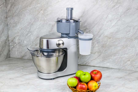 Modern food processor with juicer and plate with apples on kitchen tableの写真素材