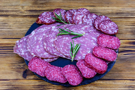 Sliced dry smoked salami sausage on slate board