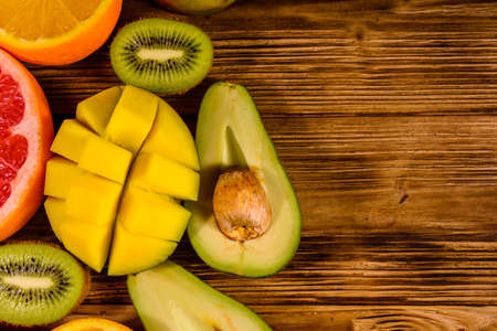Still life with exotic fruits. Mango, oranges, avocado, grapefruit and kiwi fruits on rustic wooden table. Top viewの写真素材