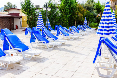Empty chaise lounges and sun umbrellas near swimming poolの写真素材
