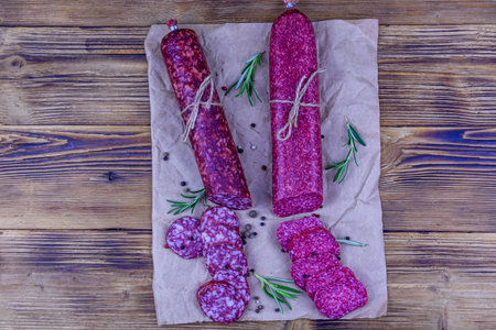 Dry smoked salami sausage on wooden background. top view