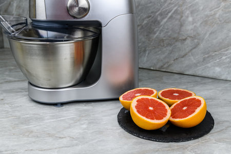 Modern food processor with citrus press and grapefruits on kitchen table