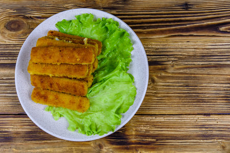 Baked fish sticks and lettuce leaves in plate. top viewの写真素材
