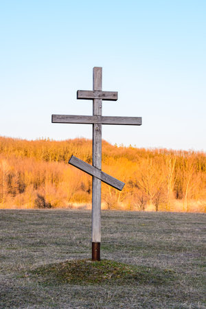 Old wooden cross on meadow against skyの写真素材