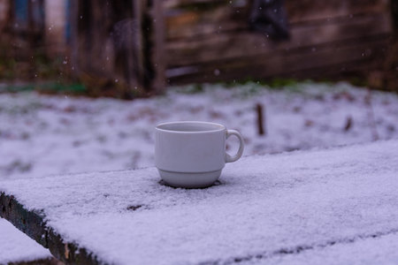 Cup with hot coffee on wooden table in winterの写真素材