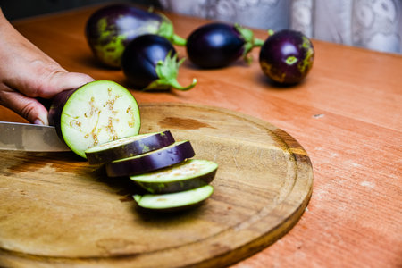 Woman cutting eggplant on a cutting boardの写真素材