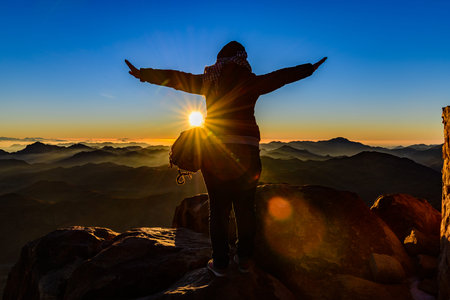 Young woman meets the dawn at the top of Mount Sinai. Sinai peninsula, Egypt