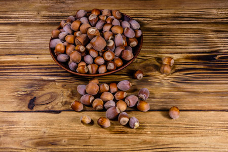Plate with pile of hazelnuts on wooden table