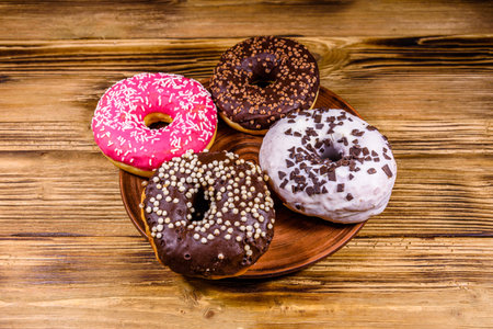 Plate with glazed donuts on wooden tableの写真素材