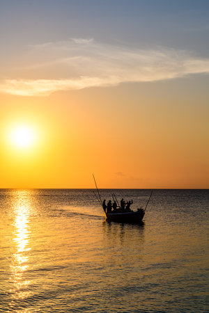 Silhouettes of fishermen in boat against sunset. Zanzibar, Tanzaniaの写真素材